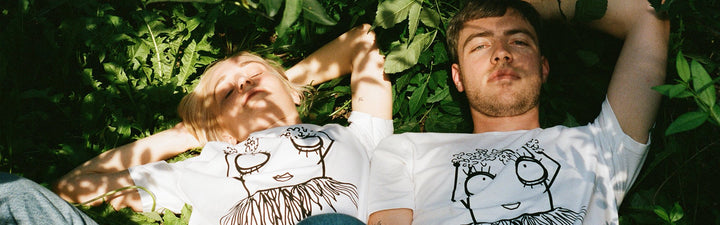 Couple lying in the meadow with white Quipster Hula T-shirts 
